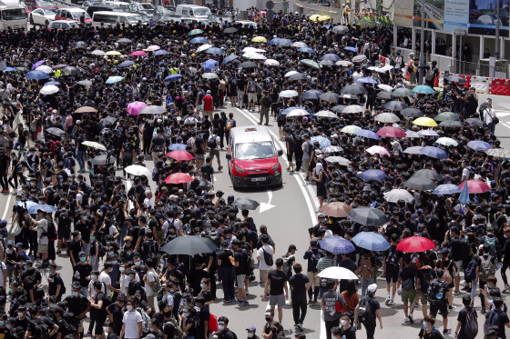 Image: A taxi makes its way through a crowd of protesters gathered on a street near government offices in Hong Kong,