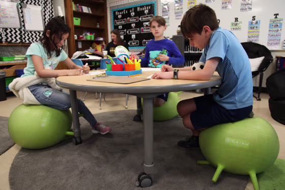 Second-graders, from left, Sarai Sepulveda, Jaxson Murchison and Parker Dubey balance on stability balls as they complete an art project at Thomas Hooker Elementary School in Meriden, Connecticut.