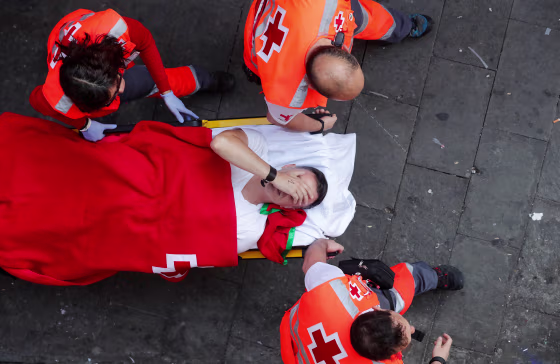Image: A reveller is helped by medical staff during the running of the bulls at the San Fermin festival in Pamplona, Spain,