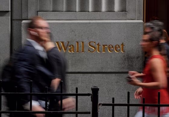 Image: People walk on Wall St. outside the NYSE in New York