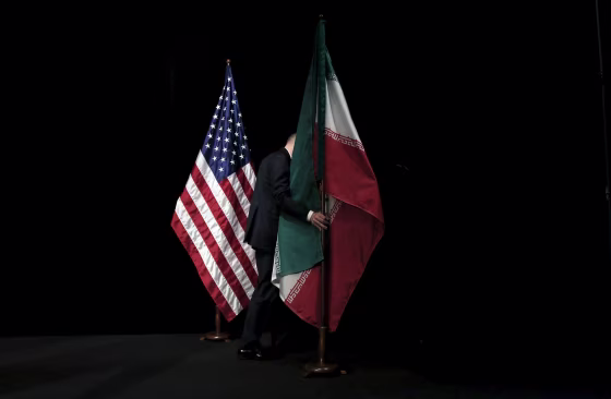 Image: A staff member removes the Iranian flag from the stage after a group picture with foreign ministers and representatives during the Iran nuclear talks at the Vienna International Center in Vienna
