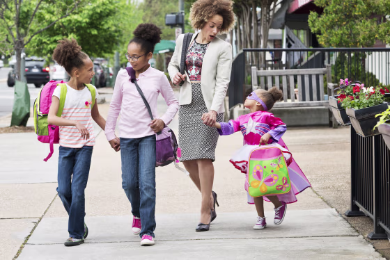 Image: Mixed Race woman walking daughters to school in city