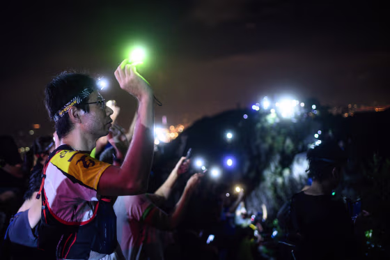 Image: A protester lights up a laser beam at the hill top of Lion Rock in Hong Kong