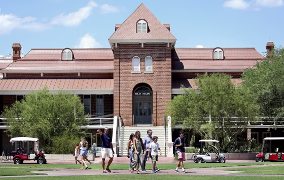 In this Aug. 17, 2018, photo, families and students walk in front of Old Main along the University of Arizona Mall the week before classes start in Tucson, Ariz.