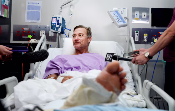 Image: Neil Parker speaks to reporters from his hospital bed while recovering after he crawled through Australian woodland for two days with a broken leg and arm on Sept. 18, 2019.