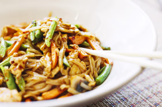 Image: Close up of stir-fried Thai chicken in bowl plus chopsticks