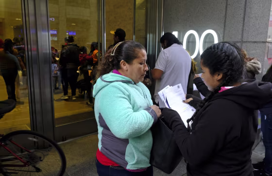 Two women look over their documents by a line snaking around the block outside a U.S. immigration office with numerous courtrooms on Jan. 31, 2019, in San Francisco.