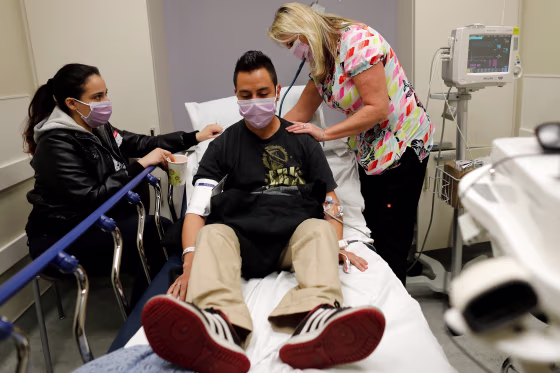 Image: Emergency room nurse Christine Bauer treats Joshua Lagade of Vista, California, for the flu as his girlfriend Mayra Mora looks on in the emergency room at Palomar Medical Center in Escondido, California, on Jan. 18, 2018.