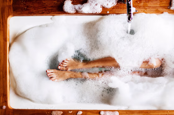 Woman legs in bath foam. Top view. Enjoying and relaxation in spa hotel