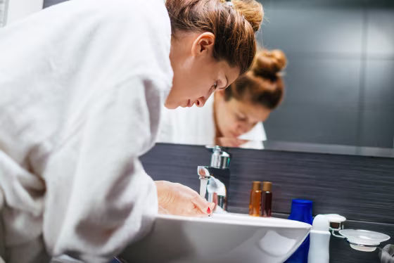 woman in bathroom washing her face