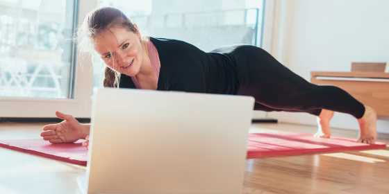 Woman doing sport in front of laptop at home.