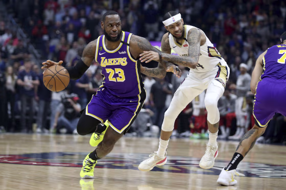 Los Angeles Lakers forward LeBron James (23) dribbles the ball past the defense of New Orleans Pelicans forward Brandon Ingram (14) in the first half of an NBA basketball game in New Orleans on March 1, 2020.