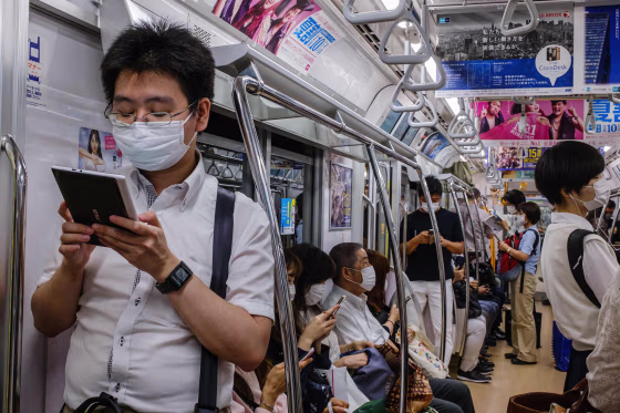 Image: Commuters wearing face masks travel on a train in Tokyo on July 16, 2020.