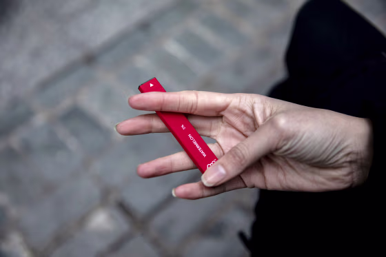 A woman holds a Puff Bar flavored disposable vape device in New York on Jan. 31, 2020.
