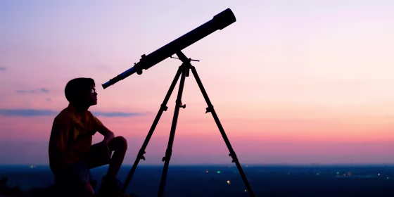 Person stargazing at night with a telescope. Shop the best telescopes and binoculars to watch meteor showers.