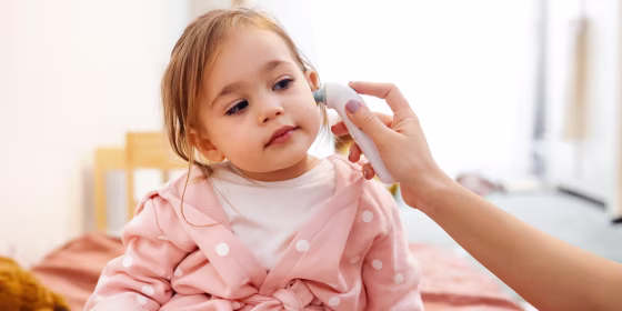 Little girl getting temperature taken with ear thermometer