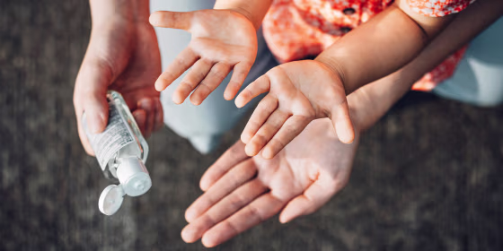 adult applying hand sanitizer to childs hands