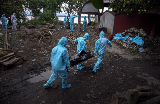 Image: Health workers wearing personal protective equipment carry the body of a COVID-19 victim for cremation in Gauhati, India,