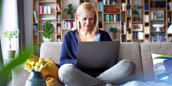 woman sitting in living room using laptop