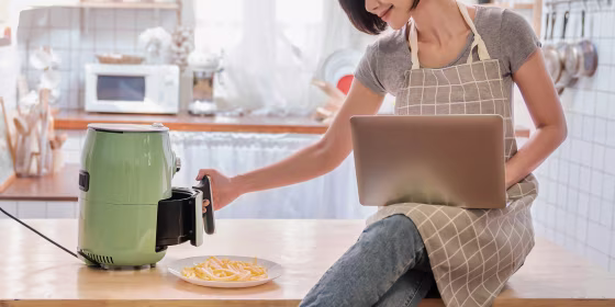 woman sitting on kitchen counter using air fryer