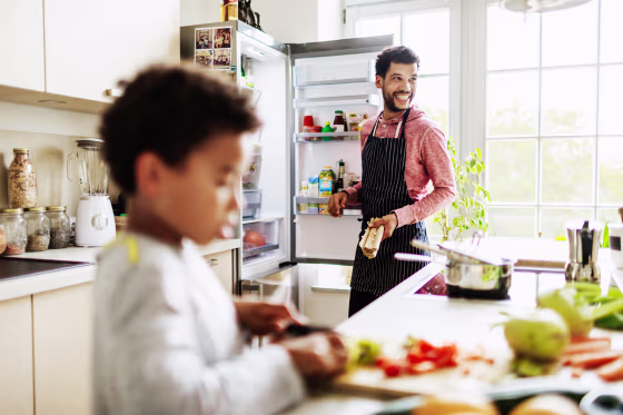 Image: Single Dad Smiling While He Prepares Lunch For Son At Home