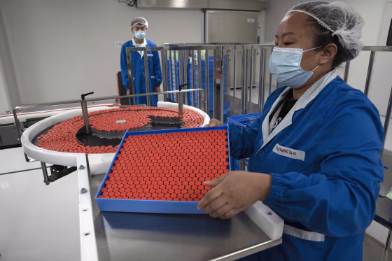 Image: A worker feeds vials for production of SARS CoV-2 Vaccine for COVID-19 at the SinoVac vaccine factory in Beijing