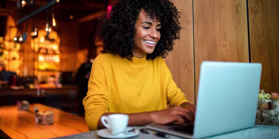 Smiling woman using laptop at the bar.