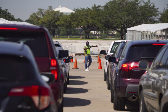 Image: An election worker guides voters in cars at a drive-through mail ballot drop-off site at NRG Stadium on Oct. 7, 2020 in Houston, Texas.