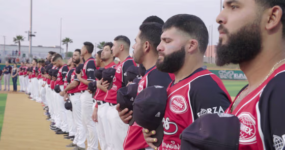 Members of the Tecolotes de los Dos Laredo, a binational professional baseball team with home stadiums in Nuevo Laredo, Mexico, and Laredo, Texas, stand for the U.S. National Anthem in a scene from the Showtime documentary "Bad Hombres."
