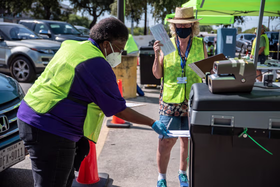 Image: Workers drop voters ballots into a secure box at a ballot drop off location on Oct. 13, 2020 in Austin, Texas.