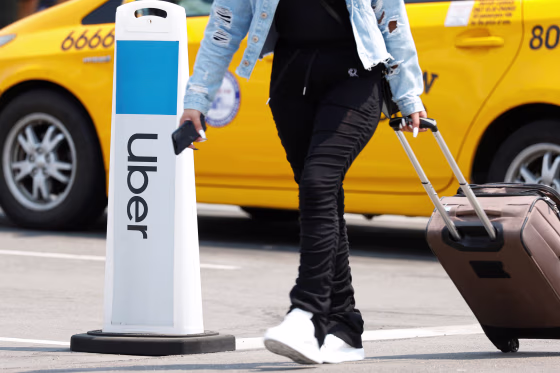 Image: Traveler arrives as Uber and Lyft drivers demonstrate over basic employee rights in California