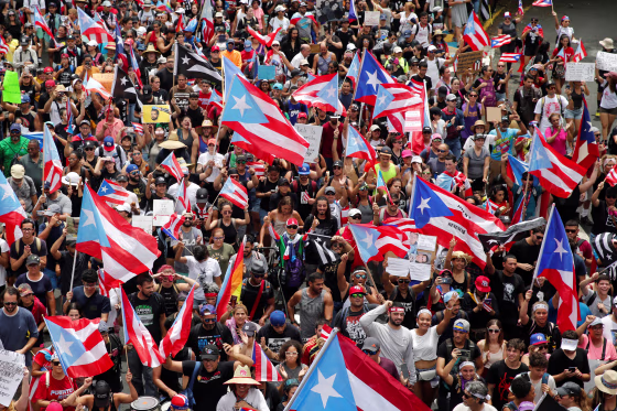 People wave Puerto Rican flags as they attend a rally to celebrate the resignation of Puerto Rican Governor Ricardo Rossello in San Juan