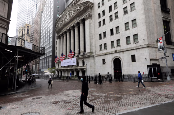 Image: People wearing protective face masks walk outside New York Stock Exchange in New York