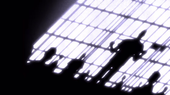 Image: Silhouettes of a prisoners in a packed cell behind bars.