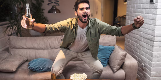 Man watching the Super Bowl in his house with beer and popcorn
