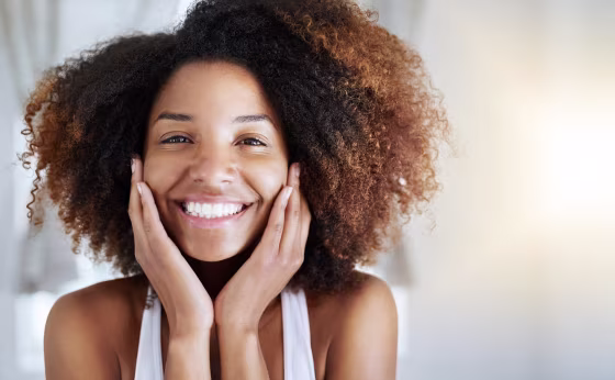 Smiling woman with curly hair. These are the 12 best natural hair products of 2021. Shop the products that will promote healthier hair growth, shine, and movement for your natural hair.