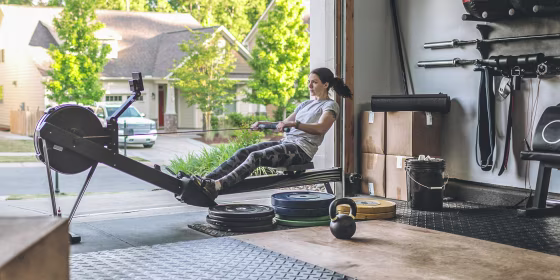 Woman rowing on her at-home rower in her garage. These are the best affordable rowers all under $500. Use this guide to help you find the best rower for your home from Amazon, Walmart and more.