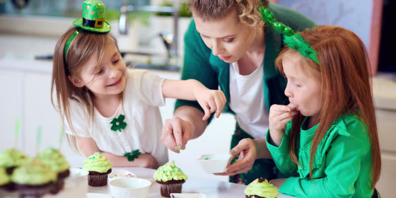 Mother and her daughters wearing St. Patricks Day decor and decorating cupcakes