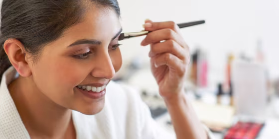 Woman using an eye shadow brush to apply eye shadow from her pallette