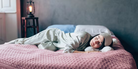 Woman sleeping on her bed in a matching silky green pajama set