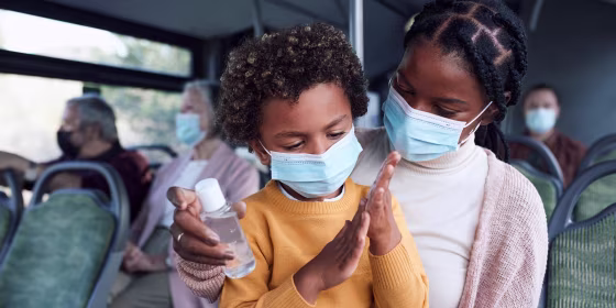 Mother giving her son hand sanitizer while on a bus