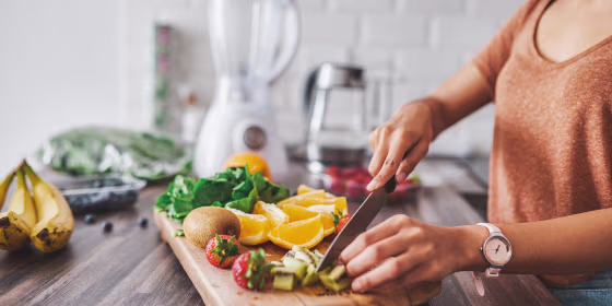 Woman in the kitchen chopping fruits on her wooden cutting board