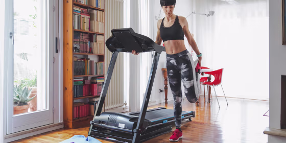 Woman in her house, stretching next to her treadmill