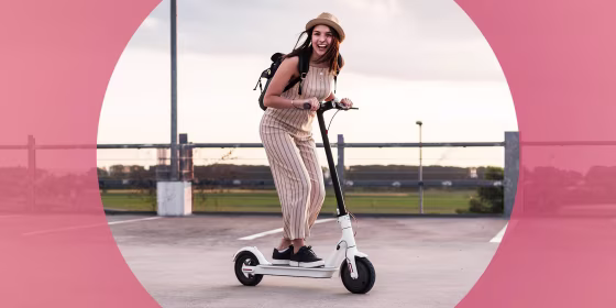 Woman in a jumpsuit and a hat, riding her white electric scooter