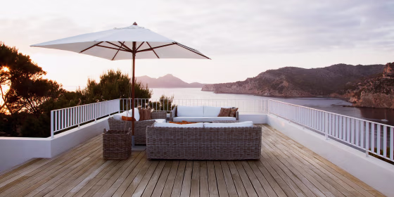 Image of patio white wicker furniture with an umbrella overlooking a beautiful ocean view