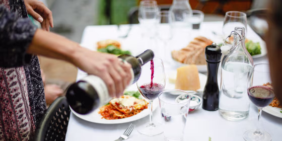 Woman pouring red wine at dinner