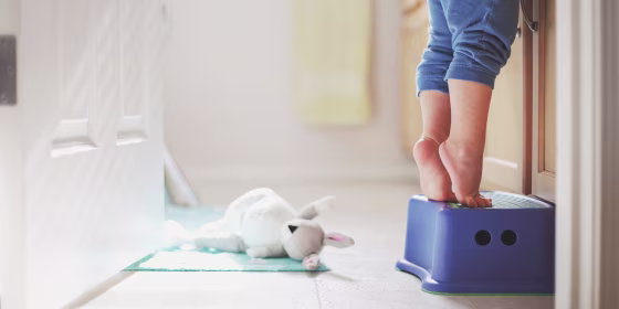 Small child toddler trying to reach the fosset on the step stool in the bathroom