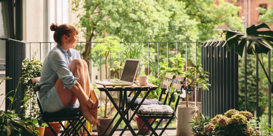 Smiling woman looking at her laptop on balcony
