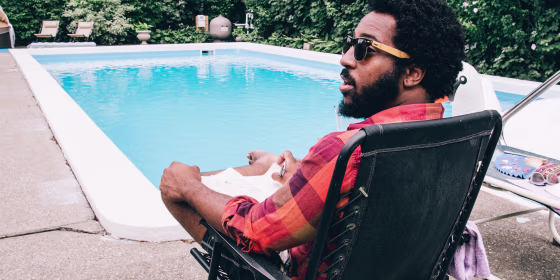 Man relaxing on a black chair by the pool