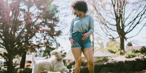 Woman playing at the park with her dog, wearing Denim shorts